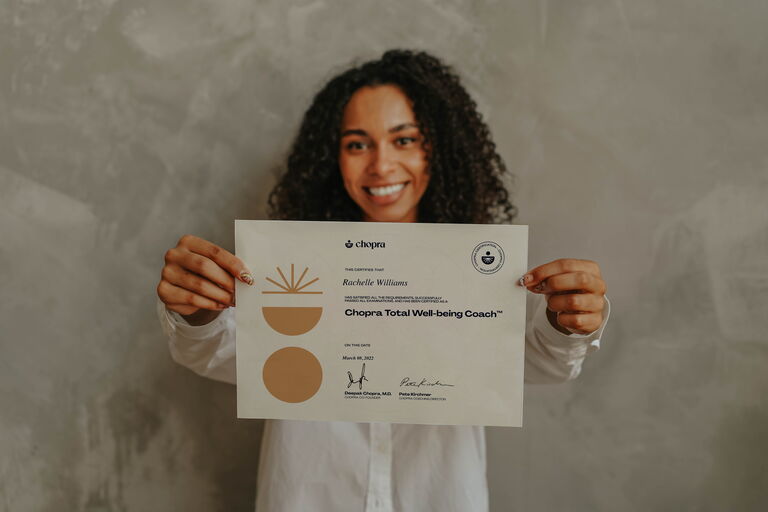 Woman holding a Coaching Chopra certificate document